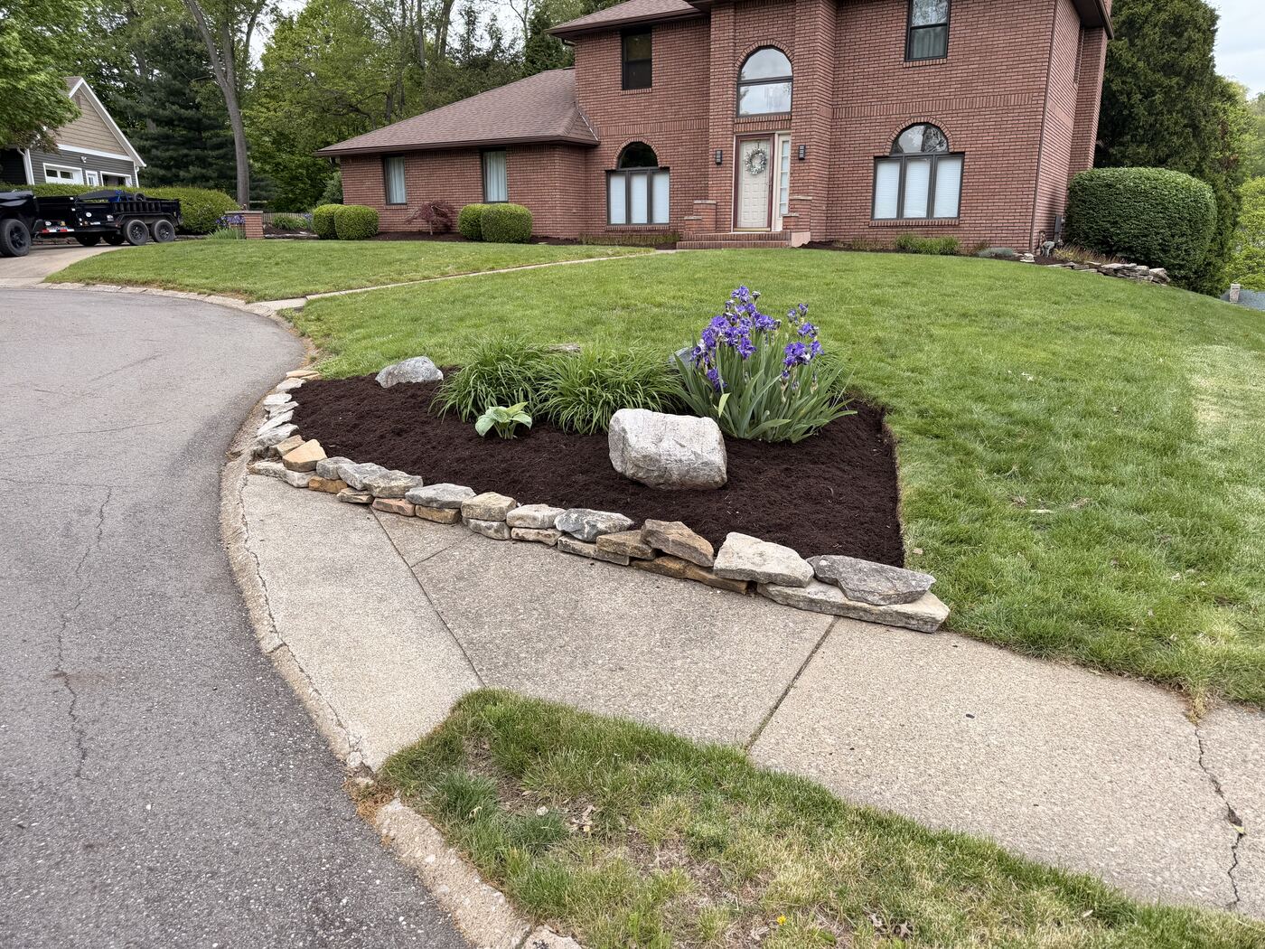 Curved landscape bed with boulder accents and iris plantings