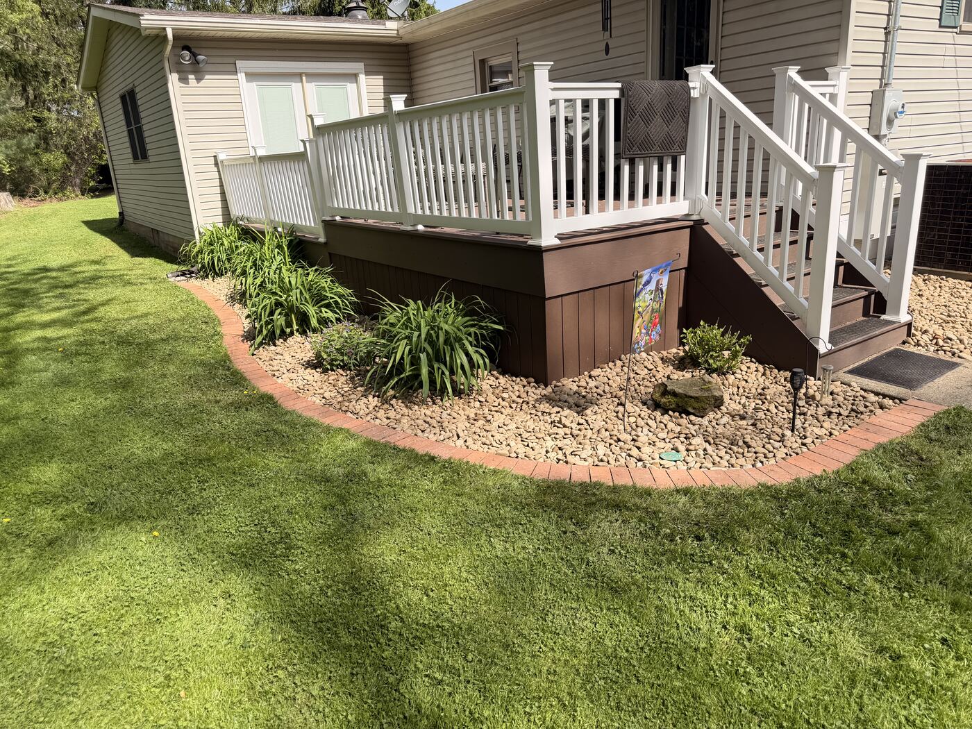 River rock bed with brick edging under a deck